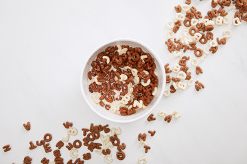 top view of bowl with chocolate and white cereal on marble surface