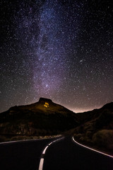 Concept of travel in amazing scenic places with long asphalt road by night and milky way stars on. the black sky