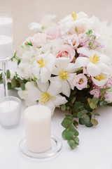 White candles and bouquet from an assortment of fresh and beautiful flowers decorate the festive table