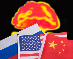 Flags of the super powers China,Russia and USA with a nuclear explosion in the background .