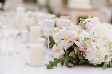 Fototapeta na wymiar Luxury decoration of the wedding table with white candles and flowers in light shades