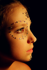 Vertical portrait of a beautiful girl with skull make-up. People, Halloween concept. Portrait of a girl with makeup from rhinestones. Female face in the darkness.