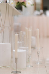 Stylish white candles in elegant glass candlesticks on a white background