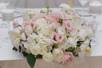 A large bouquet of light and pastel shades on the groom and bride 's table. Beautiful white, pink fresh flowers