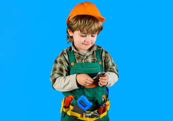 Little kid boy in builder uniform with wrench. Builder boy in helmet and tools. Child game. Tools for building. Kid repairman with tool belt. Work with tools. Repair. Kid boy as builder or repairer.