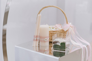 Fototapeta na wymiar A braided basket with natural rose petals, a small engagement ring box and wedding candles