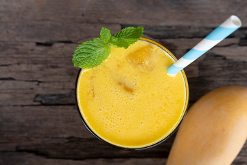 Mango smoothies colorful fruit juice milkshake blend beverage healthy high protein the yummy In glass,drink to lose weight drink isolated wood background from the top view.