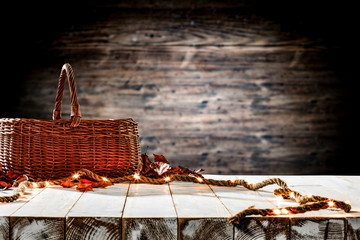 White wooden table background with brown basket and light bulbs. Blurred background and empty space for text decoration. 