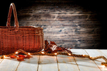 White wooden table background with brown basket and light bulbs. Blurred background and empty space for text decoration.