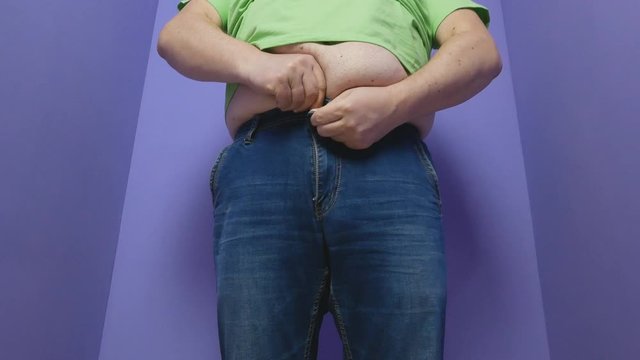 The fat man zips the zipper on the jeans. weight problems, diet, overweight, obesity