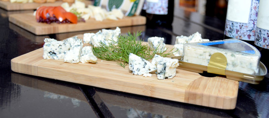 Fresh made platter with danish blu cheese pieces and green dill on wooden board
