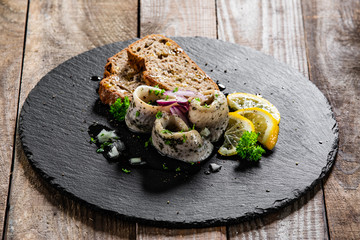 Marinated herring fillets with slices of bread on black stone