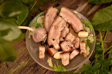 Homemade salty fat with cold cuts. Spicy lard with garlic, onions and parsley. Lunch in the village. Photo in warm colors, on the street. Table made of natural aged wood.