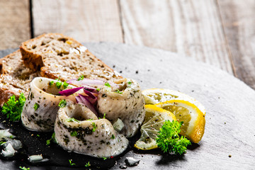 Marinated herring fillets with slices of bread on black stone