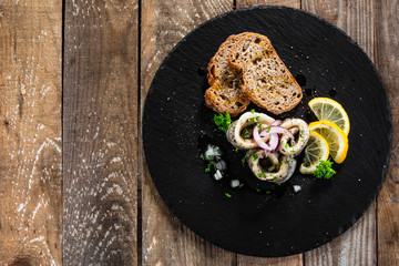 Marinated herring fillets with slices of bread on black stone