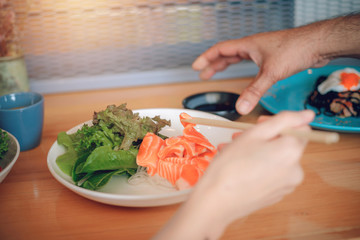 The hand is using a chopsticks to squeeze the salmon.