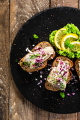 Marinated herring fillets on slices of bread on black stone