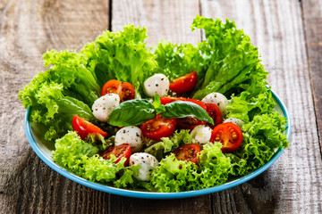 Salad with mozzarella cheese and cherry tomatoes on wooden table