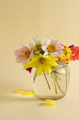 Flowers in a glass jar on a yellow background.
