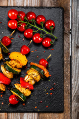 Grilled shashliks with chicken and baked potatoes on black stone