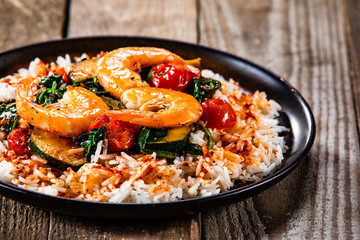 Shrimps with white rice and vegetables on wooden table