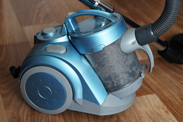 Blue vacuum cleaner on wooden floor so close