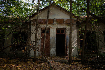Old abandoned building in the forest with dark doorway