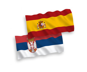 National vector fabric wave flags of Serbia and Spain isolated on white background. 1 to 2 proportion.