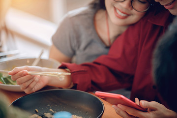 A woman playing a smartphone in a restaurant with a smiling face