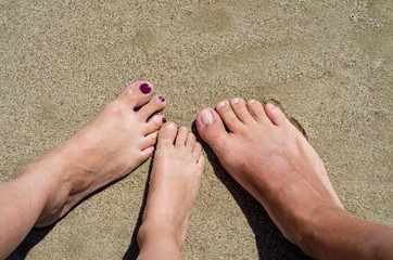 Bare feet of the whole family on the beach