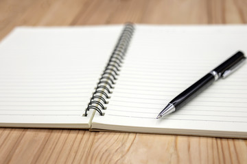 Blank notebook with a pen on a wooden table
