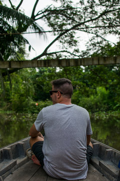 Imagen de un chico caucásico, mirando hacia la jungla, en el río del delta del Mekong, en Vietnam