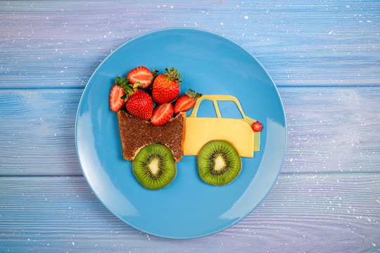 Kids Food Idea. Children's Breakfast With Sandwich And Berries. Funny Car Truck  Sandwich With Chocolate Paste, Strawberries, Kiwi And Cheese. Top View