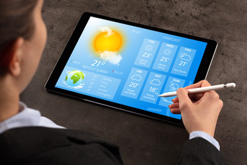 Business woman checking weekly weather forecast on tablet