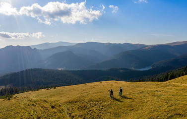 Aerial view. Epic shot of two mountain bikers on top of the mountain looking down the valley....