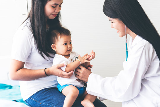 Asian Female Doctor Is Using A Stethoscope Listen To Heart Rate Of A 1 Year Old Patient That The Mother Brought For Checking  The Flu, Which Is Pandemic, To Health Care And Children Concept.