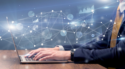 Businessman typing on laptop with linked reports charts grapghs around