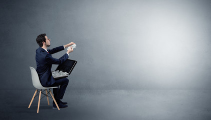 Businessman staying in an empty grey dark room with stuffs on his lap