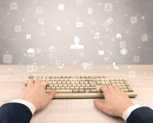 First person view of hand typing with social media concept icons around