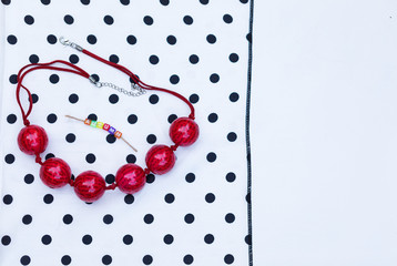 Red Stylish Beads Are On Vintage Scarf Polka Dot. The Text ‘Autumn’ is Seasonal Detail of Fashionable Composition. White Background Copy Space. Creative Top View Flat Lay Fashion Fall Composition.