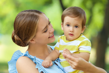 Beautiful mother with her cute baby in park on summer day