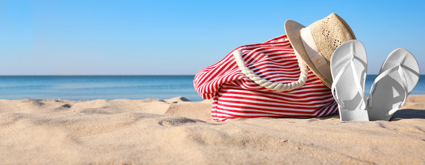 Set with stylish beach accessories on sand near sea