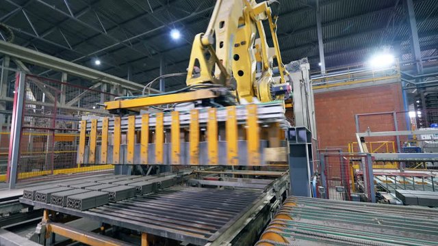 Factory arm moves bricks from a conveyor.