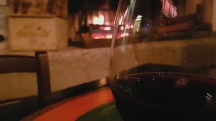 Close up of glass of red wine with a fireplace in the background, Vittorio Veneto, Italy