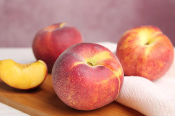 Fototapeta na wymiar Board with fresh peaches and fabric on table