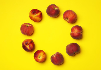 Flat lay composition with ripe peaches on yellow background, space for text