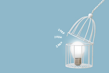 Lamp bulb in bird cage isolated on blue background, minimal idea