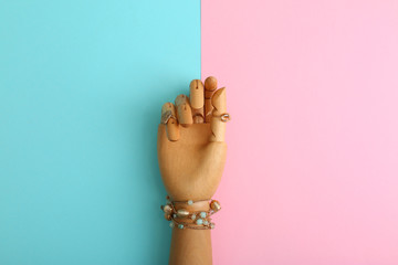 Decorative arm with stylish jewelry on color background, top view