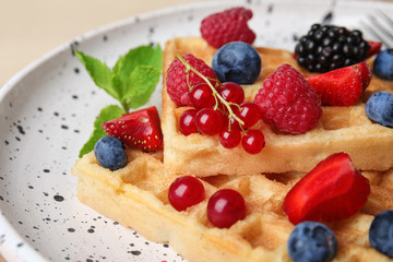 Delicious waffles with fresh berries served on table, closeup