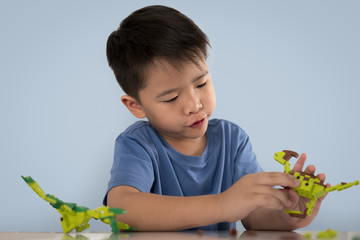 Portrait of cute asian boy playing with colorful plastic toy bri